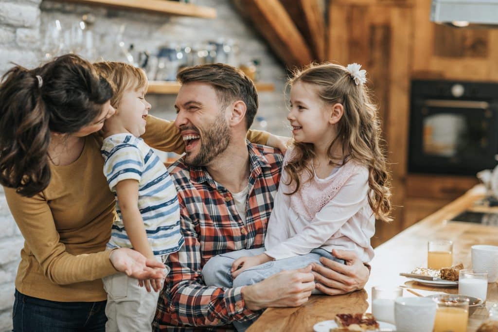 Young happy parents having fun with their children during breakfast time at home