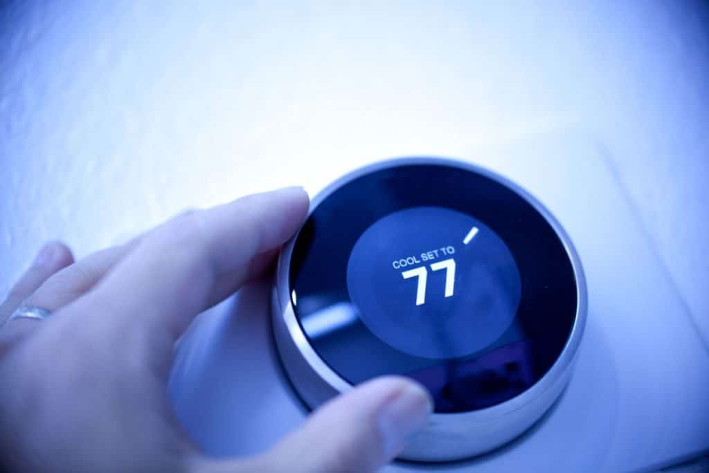 man controlling temperature on a nest thermostat