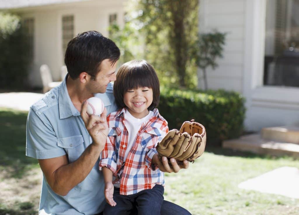 dad and son practicing baseball in front yard