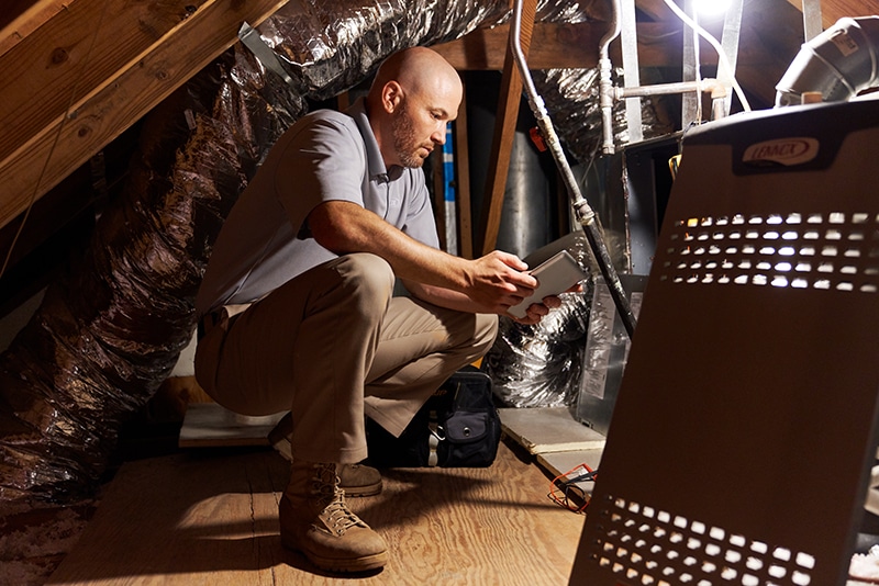 Technician in the attic troubleshooting an issue with the furnace